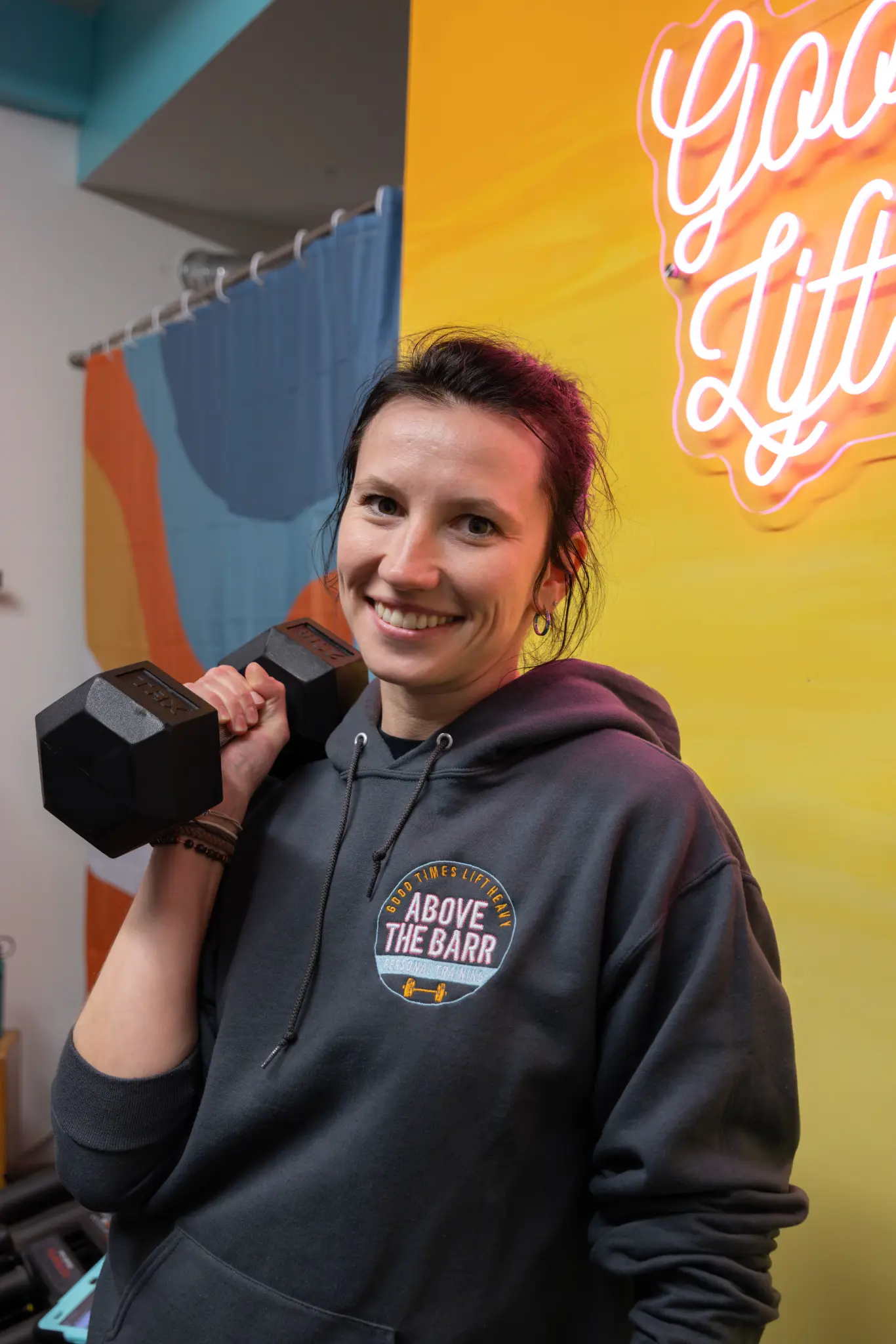 Above The Barr member smiling with a dumbbell during her training session